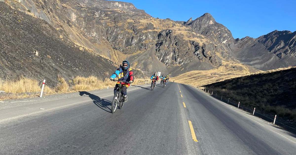 Cyclists riding downhill on the road with mountains in the background near Death Road in Bolivia