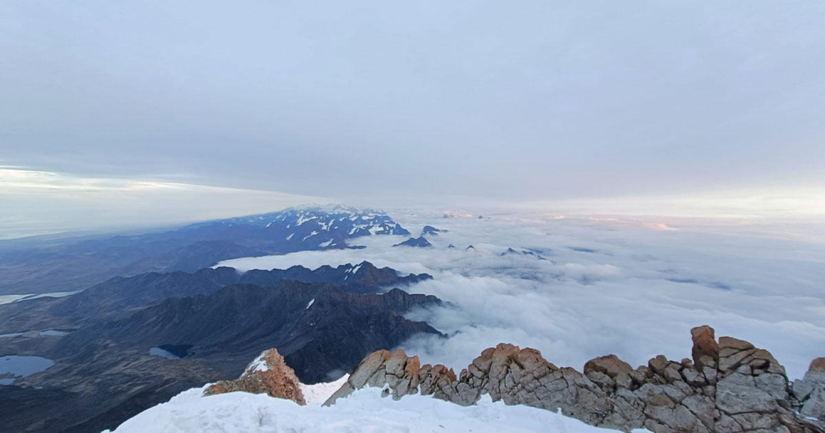 Panoramic view of snow-covered peaks and clouds from the summit of Huayna Potosí in Bolivia