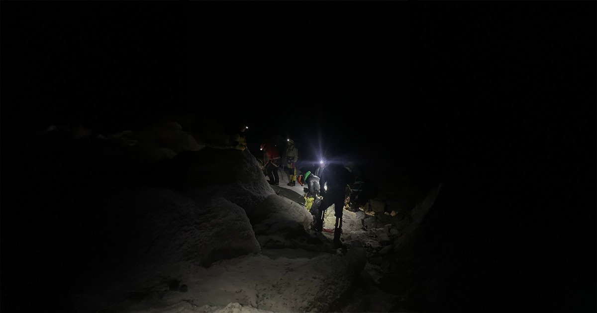 A team navigating through the dark, lit only by headlamps, during the early hours of the ascent.