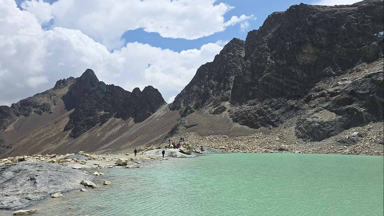 Emerald green lagoon surrounded by rocky mountains at Charquini in Bolivia