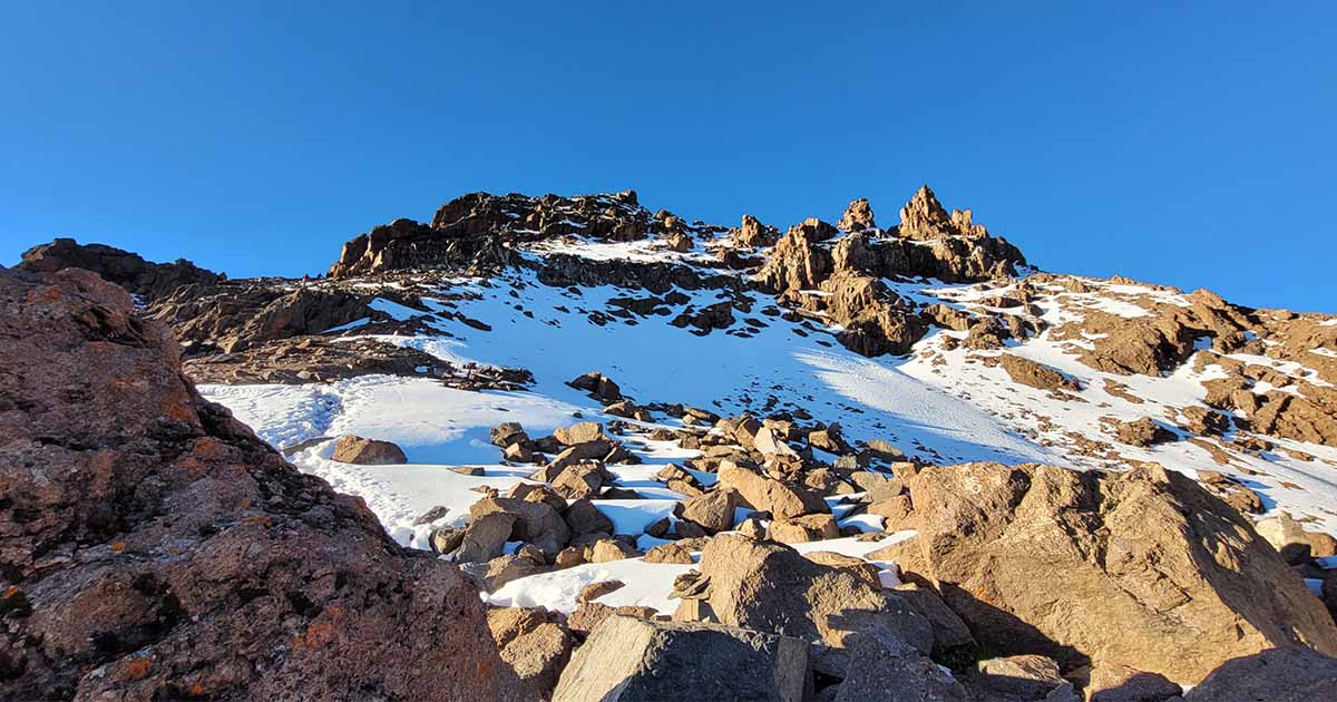 Snowy and rocky mountain terrain under a clear blue sky during the day