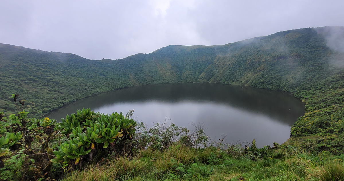 A tranquil volcanic crater lake in Rwanda surrounded by green hills