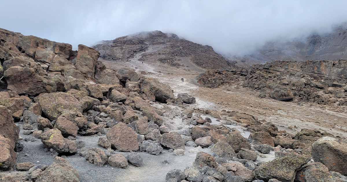 A rocky and barren landscape leading towards a mist-covered summit