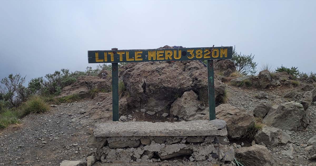 Signpost for Little Meru peak at 3820 meters with rocky terrain in the background