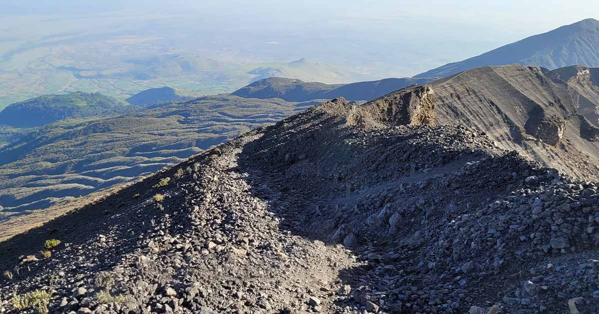 Rocky trail on Mount Meru with a view of the landscape below during descent