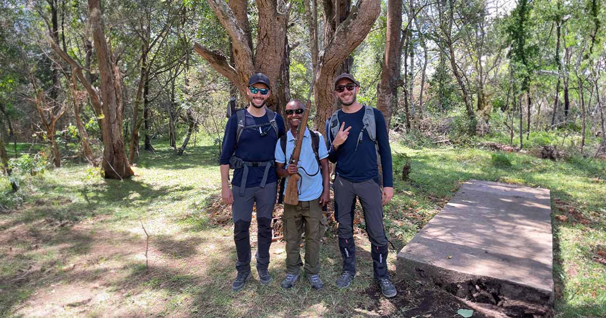 Two hikers and a ranger with a friendly pose in a forest during a trek