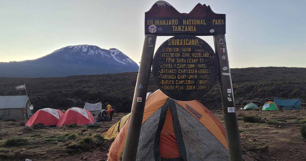 A signpost at Shira 1 Camp detailing elevation and distance to Kilimanjaro's summit and other camps