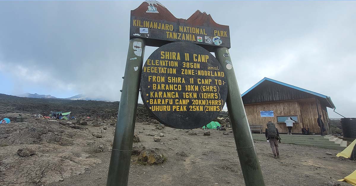 A signpost at Shira 2 Camp detailing elevation and distance to Kilimanjaro's summit and other camps