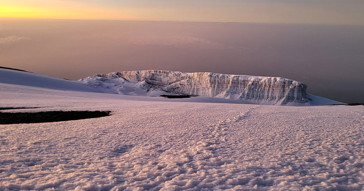 A rocky and icy mountain peak against a backdrop of blue sky and clouds