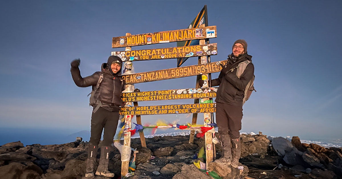 Summit sign at Uhuru Peak, the highest point of Mount Kilimanjaro, with us celebrating